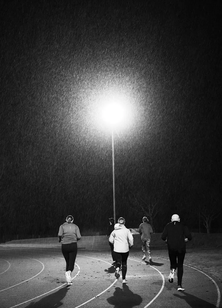 Runners on a track at night